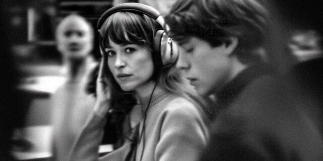 2025-12-11-Woman-With-Headphones-Glancing-Amid-Crowd-Human-Connection-Awareness.jpg