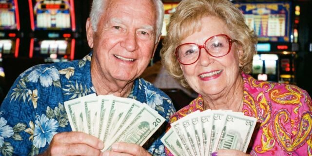 2026-01-18-Elderly-Couple-Holding-Cash-Money-At-Casino-Slot-Machines-Big-Money-Luck-Fortune.jpg