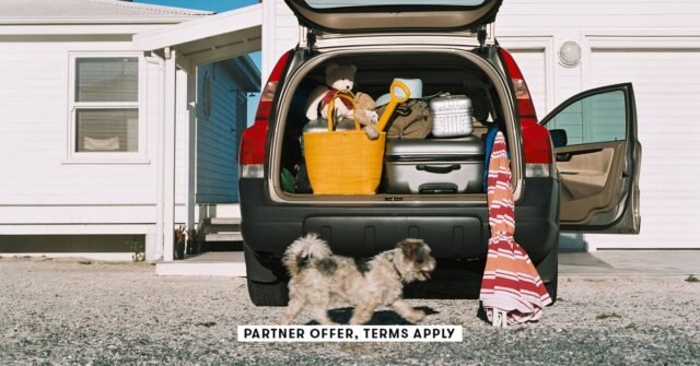 SOCIAL-IMAGE_PARTNER-OFFER-TERMS-APPLY_Dog-running-by-car-full-of-luggage-for-summer-roadtrip_Image.jpeg